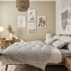 Przytulna sypialnia w stylu boho z łóżkiem, biurkiem z wiklinowym krzesłem i dekoracjami ściennymi.
