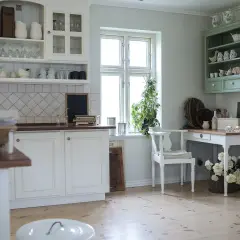 Biała kuchnia w stylu rustykalnym z widocznymi pilastrami meblowymi na szafkach i komodzie.