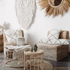 Przytulny salon w stylu boho z wiklinowymi meblami, makramą na ścianie i roślinami.