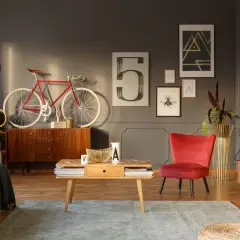 Stylowy salon z odnowionymi meblami PRL: komoda, stolik kawowy, fotel i gramofon. Czerwony rower na ścianie dodaje charakteru.