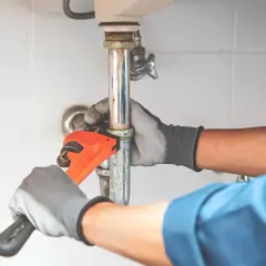 Hydraulik dokręca rurę pod zlewem, by wyeliminować hałas przy puszczaniu wody.