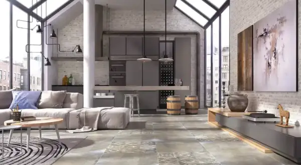 Nowoczesny salon z aneksem kuchennym, gdzie dominują industrialne elementy. Na podłodze pięknie prezentuje się gres szkliwiony o wzorze imitującym beton i kamień.