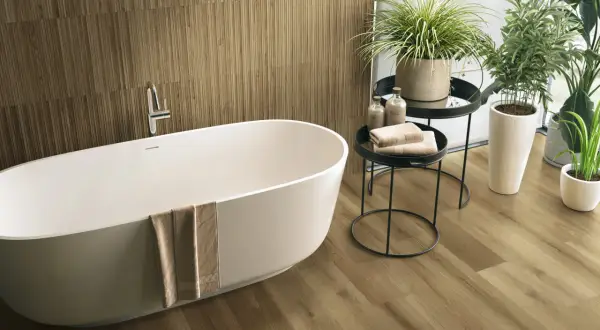 Elegancka łazienka z wanną i podłogą imitującą drewno. Fuga do płytek drewnopodobnych idealnie komponuje się z naturalnym wyglądem drewna.