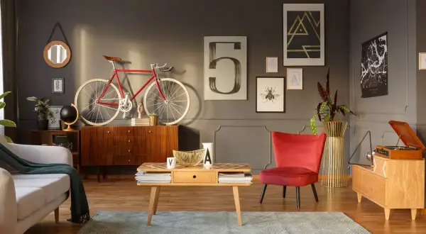 Stylowy salon z odnowionymi meblami PRL: komoda, stolik kawowy, fotel i gramofon. Czerwony rower na ścianie dodaje charakteru.