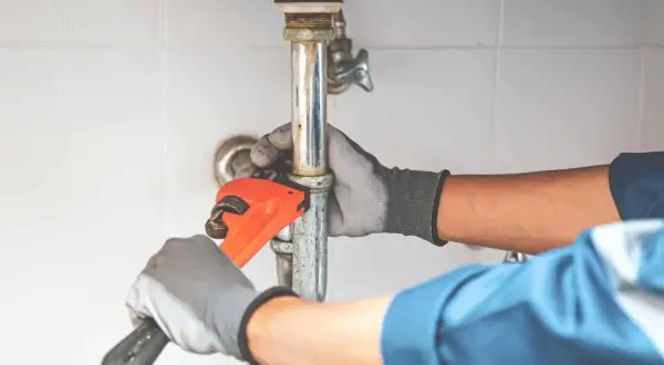 Hydraulik dokręca rurę pod zlewem, by wyeliminować hałas przy puszczaniu wody.