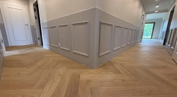 Drewniane podłogi w mieszkaniu inspiracje: jodełka klasyczna na korytarzu, eleganckie panele ścienne.
