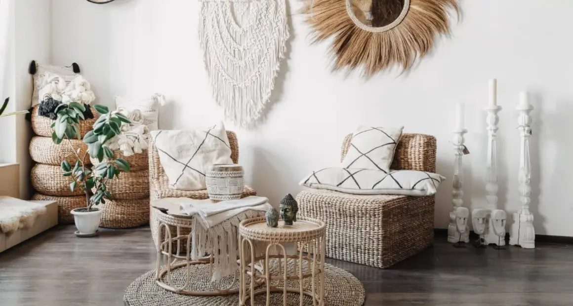 Przytulny salon w stylu boho z wiklinowymi meblami, makramą na ścianie i roślinami.