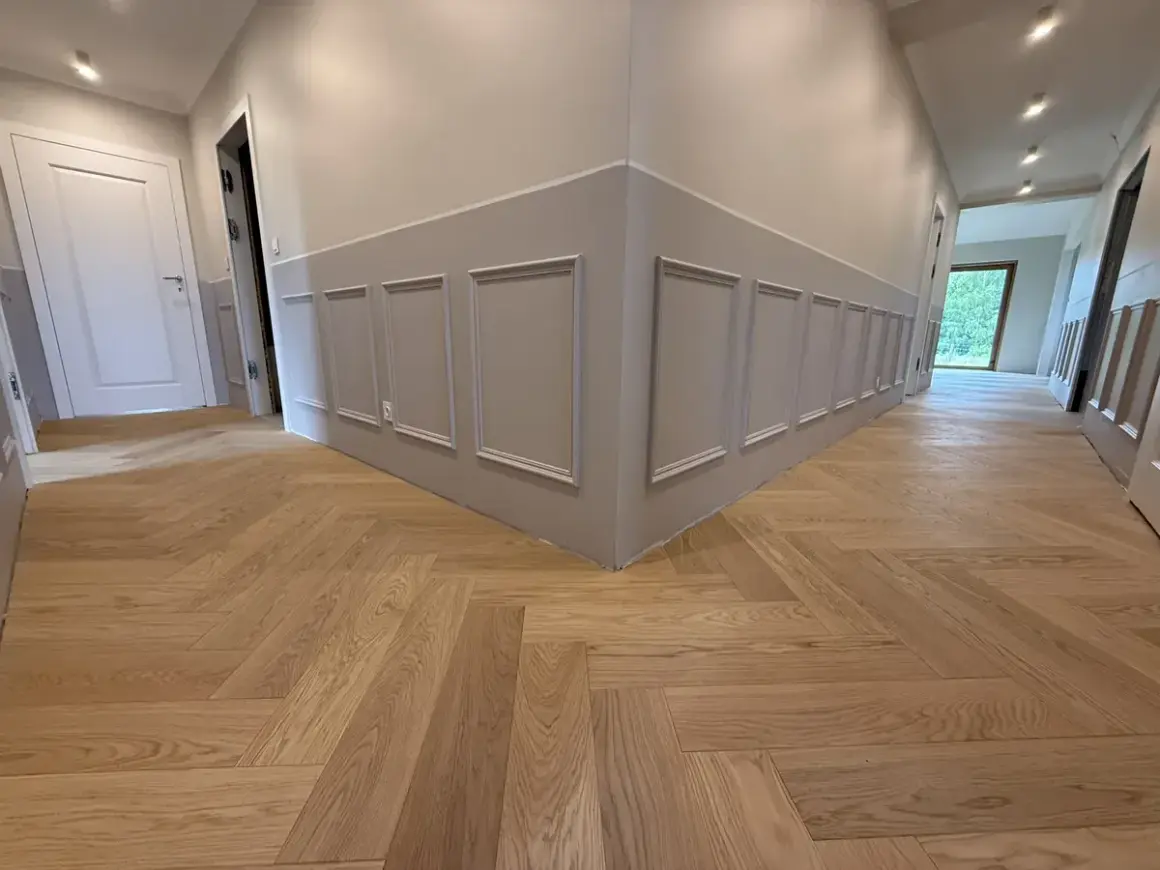 Drewniane podłogi w mieszkaniu inspiracje: jodełka klasyczna na korytarzu, eleganckie panele ścienne.