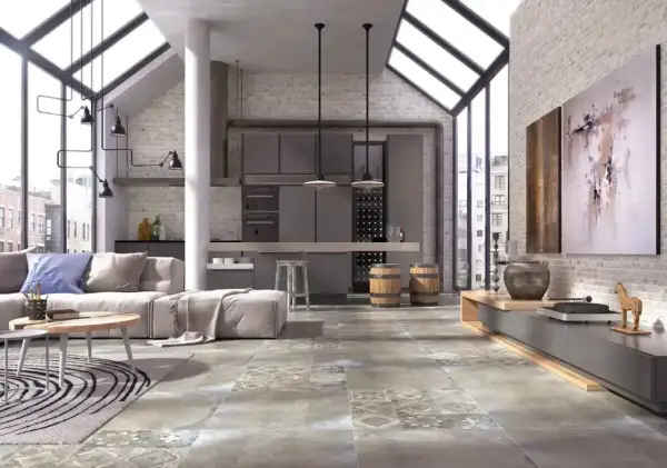 Nowoczesny salon z aneksem kuchennym, gdzie dominują industrialne elementy. Na podłodze pięknie prezentuje się gres szkliwiony o wzorze imitującym beton i kamień.
