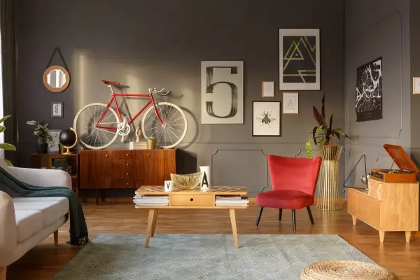 Stylowy salon z odnowionymi meblami PRL: komoda, stolik kawowy, fotel i gramofon. Czerwony rower na ścianie dodaje charakteru.
