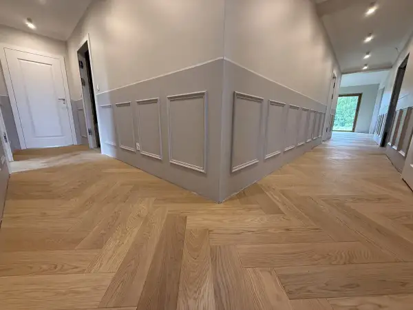 Drewniane podłogi w mieszkaniu inspiracje: jodełka klasyczna na korytarzu, eleganckie panele ścienne.